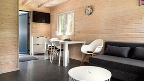 A modern interior with wooden walls, a dining area with white chairs, a sofa, and a clock on the wall.