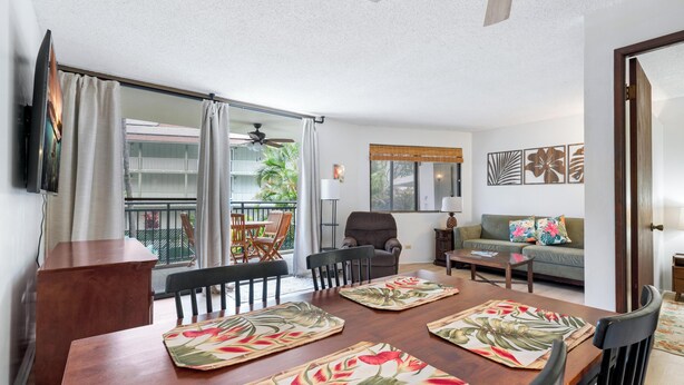 A living room with a dining table, chairs, a sofa, and a balcony with a view. - Summer Deal Downtown Kona Vacation Condo Walk to Shops Dining and Beach (Kailua Kona)