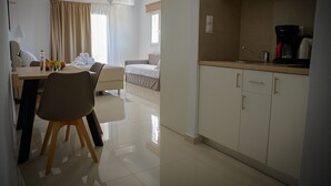 Hotellihuone, jossa on ruokailutila, pieni keittiö ja sänky.