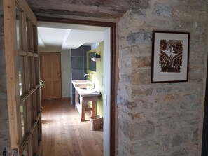 Un intérieur rustique avec une porte en bois, un mur en pierre et un tableau encadré.