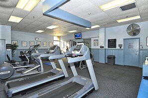 Une salle de sport équipée de tapis de course, de vélos d’appartement et d’un écran de télévision.