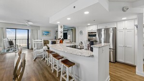 A modern kitchen with a central island, bar stools, and stainless steel appliances. - DAILY ACTIVITIES & LINENS INCLUDED*! CAPRI - 3BR Direct Oceanfront Updated Condo! (Ocean City)