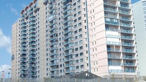 A high-rise hotel with multiple balconies, a sandy ground floor, and a clear blue sky. - DAILY ACTIVITIES & LINENS INCLUDED*! CAPRI - 3BR Direct Oceanfront Updated Condo! (Ocean City)
