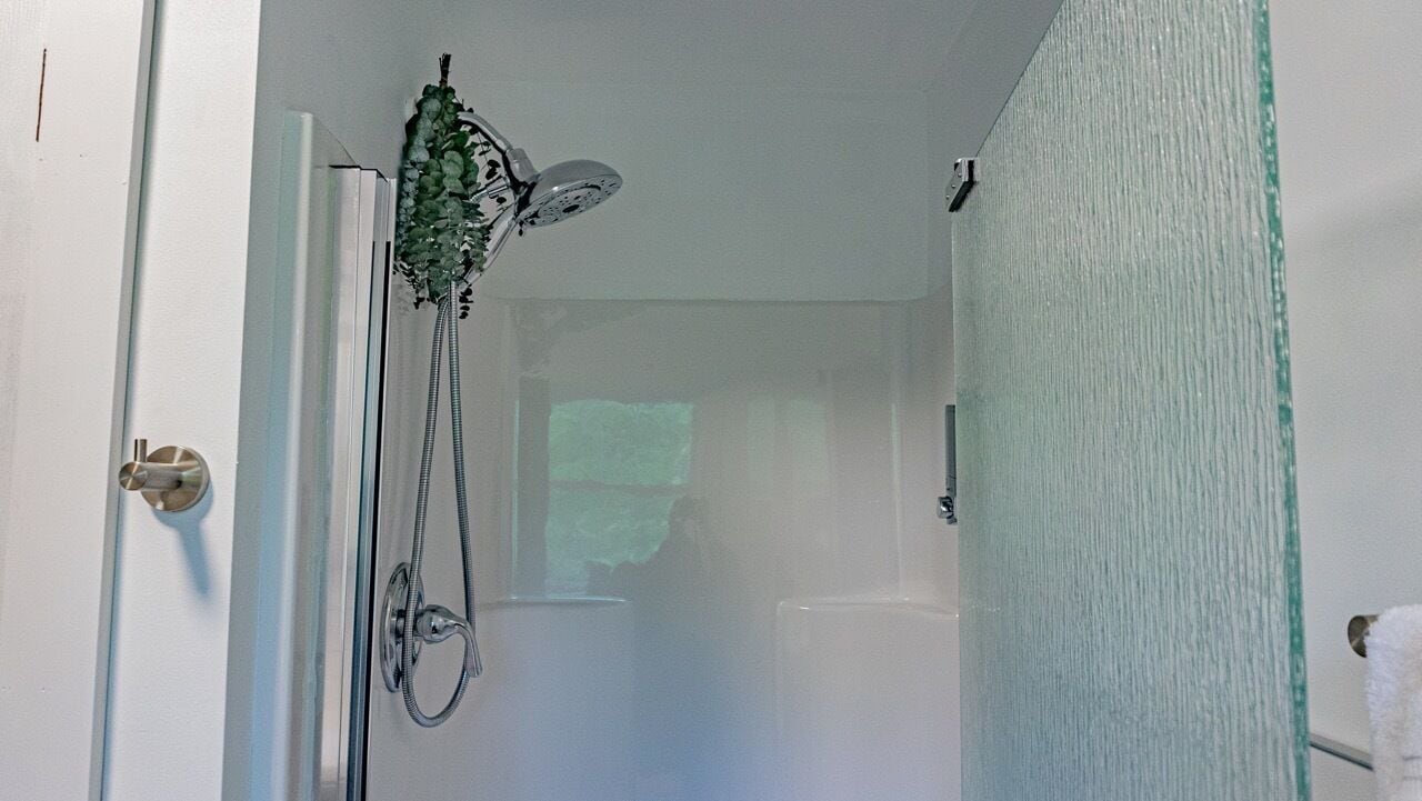 Ein Badezimmer mit Dusche, Handtuchhalter und einer Duschkabinentür aus Glas.