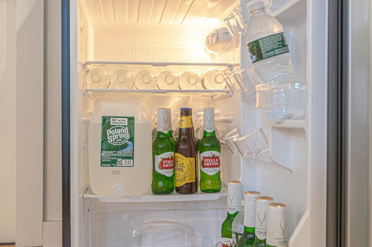A refrigerator with shelves containing bottles of beer and a carton of milk.