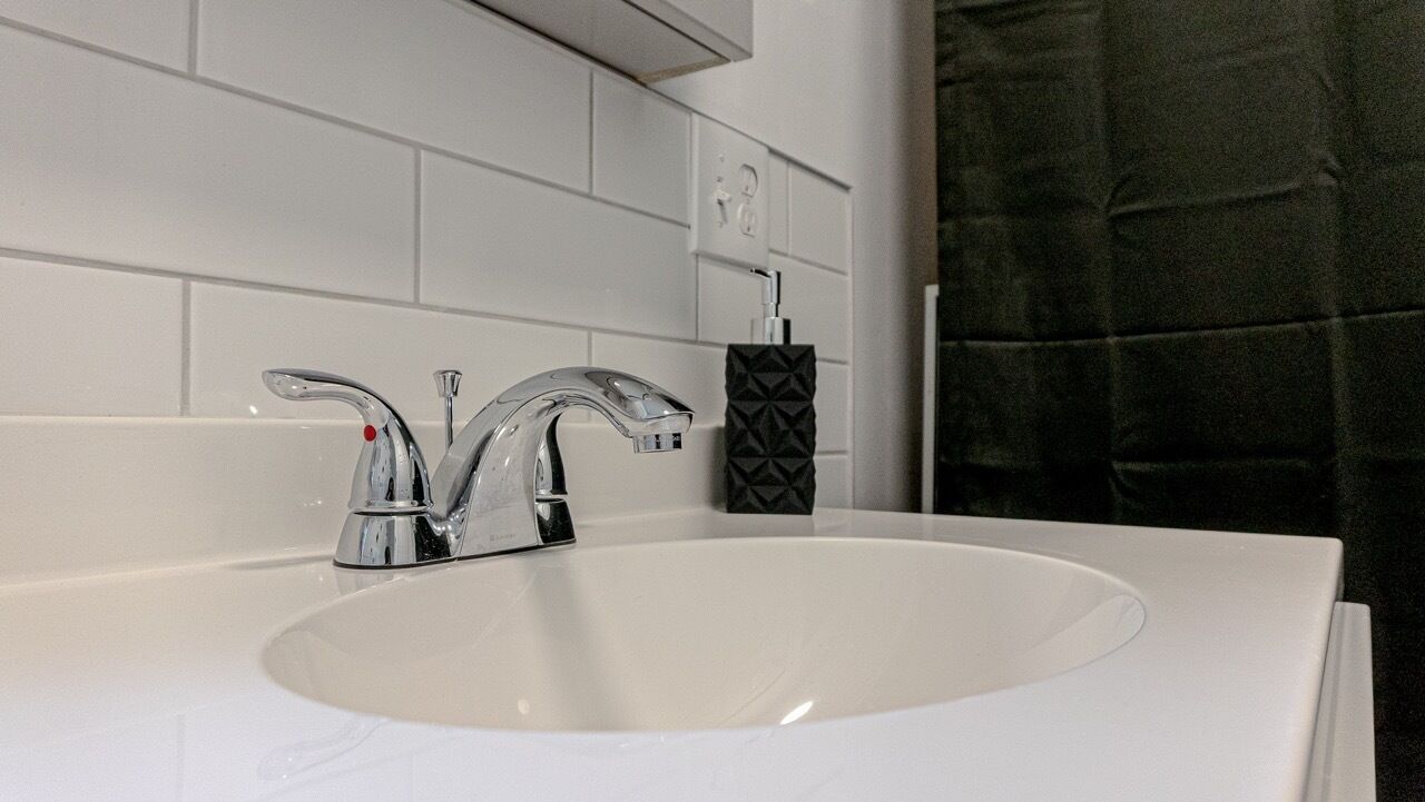 Une salle de bain moderne avec un lavabo blanc, un robinet chromé et un distributeur de savon noir.