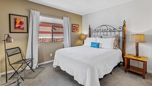 A neatly arranged bedroom with a bed, a chair, a lamp, and a window with curtains. - Sedona Condo, Close to Dining/Shopping/Hiking (Sedona)