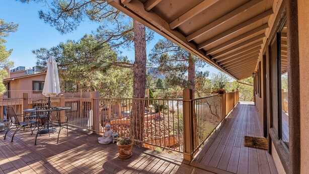 A wooden deck with outdoor furniture, a potted plant, and a statue. - Sedona Condo, Close to Dining/Shopping/Hiking (Sedona)