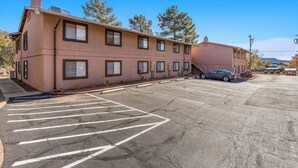 A multi-story building with a parking lot, a car parked in the lot, and trees in the background. - Sedona Condo, Close to Dining/Shopping/Hiking (Sedona)