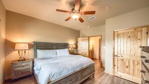 Une chambre à coucher avec un lit en bois, un ventilateur de plafond, une table de chevet avec une lampe et une armoire en bois.