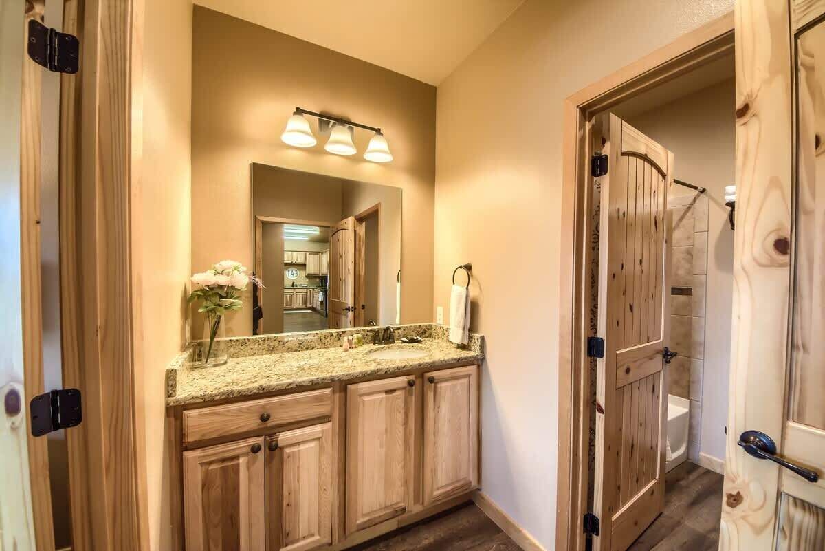 Un baño con tocador de madera, un espejo y un lavabo.