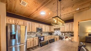 A modern kitchen with wooden cabinets, stainless steel appliances, and a large dining table.