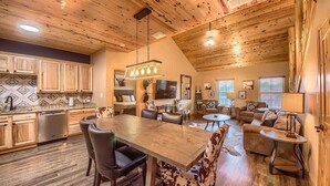 A spacious living area with a wooden ceiling, a dining table, and multiple seating arrangements.