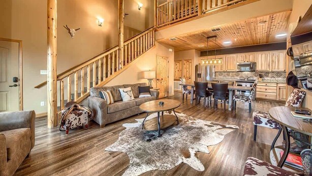 A spacious living area with a wooden staircase, a dining table, and a kitchen area.