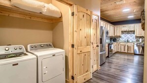 A compact kitchen with wooden cabinets, a built-in oven, and a washing machine.