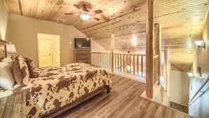 A bedroom with a bed, a ceiling fan, a TV, and a wooden staircase. - OM A8 Gruene River Two-Step at Old Mills Resort (New Braunfels)