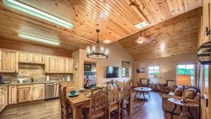A spacious living area with a wooden ceiling, a dining table with chairs, and a sofa. - OM A8 Gruene River Two-Step at Old Mills Resort (New Braunfels)