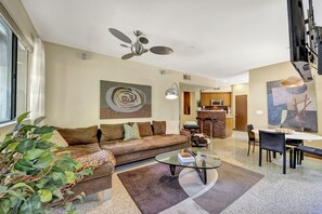 A modern living room with a brown sofa, a glass coffee table, and a dining area with a white table and chairs. - Biltmore ground level condo + 2 bdr + Office+ 3 pools + Gym in South Palm Spring (Palm Springs)