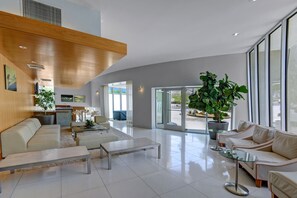 A spacious living room with a high ceiling, large windows, and a modern design. - Biltmore ground level condo + 2 bdr + Office+ 3 pools + Gym in South Palm Spring (Palm Springs)