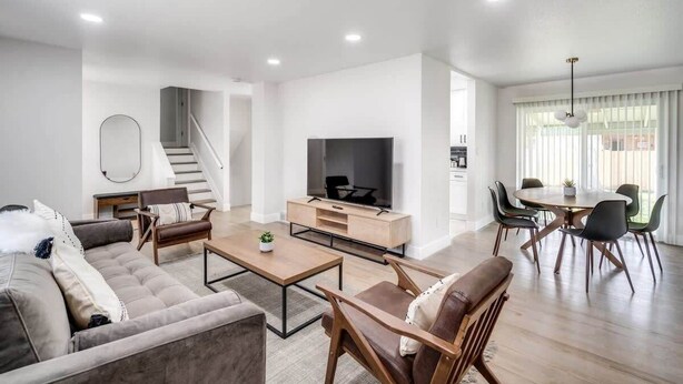 Un salon moderne comprenant un canapé, une table basse, un téléviseur et un coin repas avec des chaises.