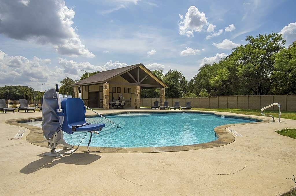 A swimming pool with lounge chairs and a covered pavilion.