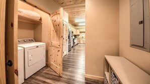 A laundry room with a washer and dryer, wooden cabinets, and a kitchen in the background.