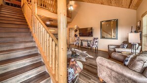 A wooden staircase leading to a lofted area with a ceiling fan, a large mirror, and a leather sofa in a rustic interior. - Old Mills Resort OM A5 3 Bedroom Condo by RedAwning (New Braunfels)