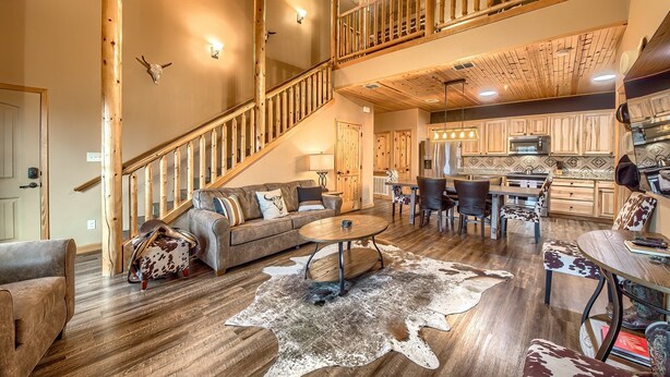 A spacious living area with a wooden staircase, a dining table with chairs, and a kitchen in the background. - Old Mills Resort OM A5 3 Bedroom Condo by RedAwning (New Braunfels)