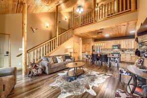 A spacious living area with a wooden staircase, a dining table with chairs, and a kitchen in the background. - Old Mills Resort OM A5 3 Bedroom Condo by RedAwning (New Braunfels)