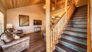 A spacious living area with a dark wood floor, a wooden staircase, and a modern fireplace. - Old Mills Resort OM A6 3 Bedroom Condo by RedAwning (New Braunfels)