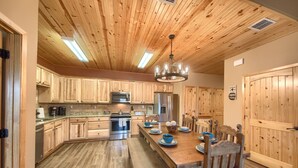 A kitchen with wooden cabinets, a stainless steel refrigerator, and a wooden dining table with chairs. - Old Mills Resort OM A6 3 Bedroom Condo by RedAwning (New Braunfels)
