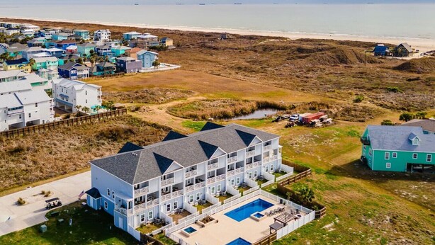 A large, multi-story building with a swimming pool and a beach view. - Dive In and Unwind: Pet-Friendly Living with Community Pools and Hot Tubs. (Port Aransas)