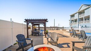 A patio area with outdoor seating, a fire pit, and a pool in the background. - Dive In and Unwind: Pet-Friendly Living with Community Pools and Hot Tubs. (Port Aransas)