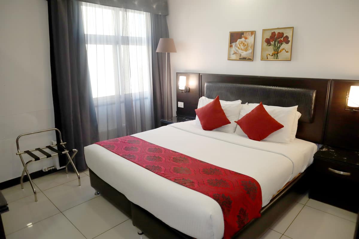 A hotel room with a large bed, a bedside table, a nightstand, a lamp, and two framed pictures on the wall.