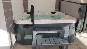 Un bain à remous doté d’un banc intégré, d’un panneau de commande et d’un tuyau.