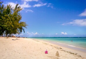A beach with clear turquoise water, a sandy shore, and a few people swimming. - Charming 5-bedroom villa with a pool near the beach (Flic en Flac)