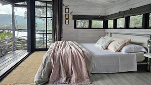 Une chambre avec un grand lit, une vue sur l’extérieur et un plafond en bois.