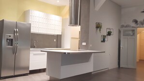A modern kitchen with a stainless steel refrigerator, white cabinetry, and a central island.