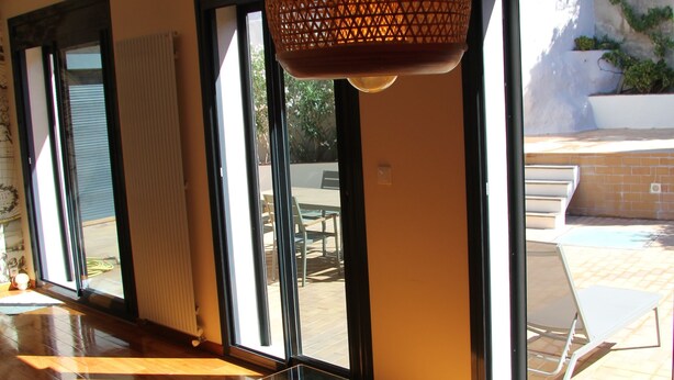 A modern interior with large windows, a glass table, and a hanging light fixture.
