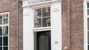 Un immeuble à la façade blanche, avec une porte noire et le numéro 23.