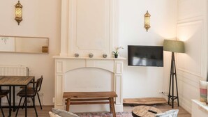 Un salon avec une cheminée, un canapé, une table à manger et un téléviseur fixé au mur.