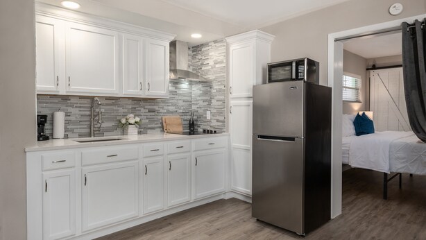 Una cocina moderna con armarios blancos, un refrigerador de acero inoxidable y un microondas.