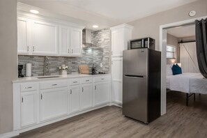A modern kitchen with white cabinets, a stainless steel refrigerator, and a microwave. - Newly Renovated Beach Retreat (Bradenton)