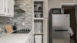 Una cocina moderna con refrigerador de acero inoxidable, microondas, tostadora y horno empotrado.
