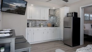 Una cocina moderna con armarios blancos, un refrigerador de acero inoxidable, un microondas y un ventilador de techo.