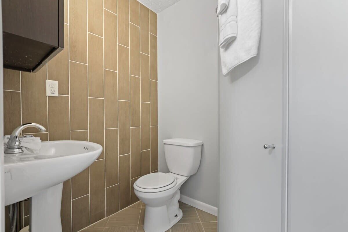 Une salle de bain avec un lavabo blanc, des toilettes et des murs carrelés.