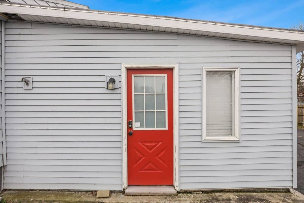 A small, single-story building with a red door and a window to the right.