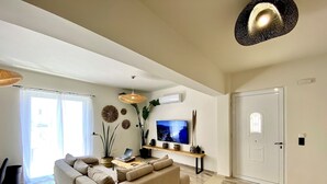 A modern living room with a sofa, TV, and decorative plants. - Ionia's apartment,3 bedrooms,Next to all amenities (Missiria)