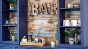 A bar area with wooden decor, shelves with glassware, and potted plants. - Mountain Time | Furnished 30+ Day Retreat (Crowsnest Pass)