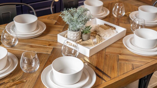 A wooden dining table set with white plates, bowls, and cutlery. - Mountain Time | Furnished 30+ Day Retreat (Crowsnest Pass)